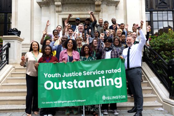 Staff and management of the Islington Youth Justice Service, joined by council leader Councillor Kaya Comer-Schwartz, gathered on the steps outside Islington Town Hall holding a sign that says "Youth Justice Service rated Outstanding"