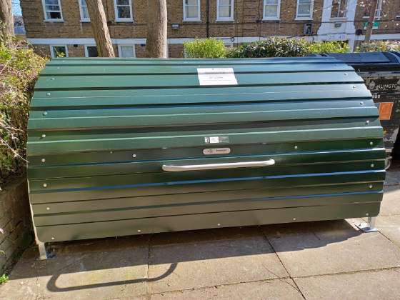 A green metal bike hangar outside Avenell Mansions