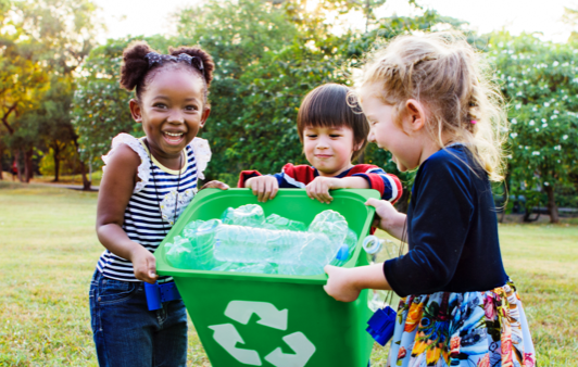 A group of children holding a recycling bin