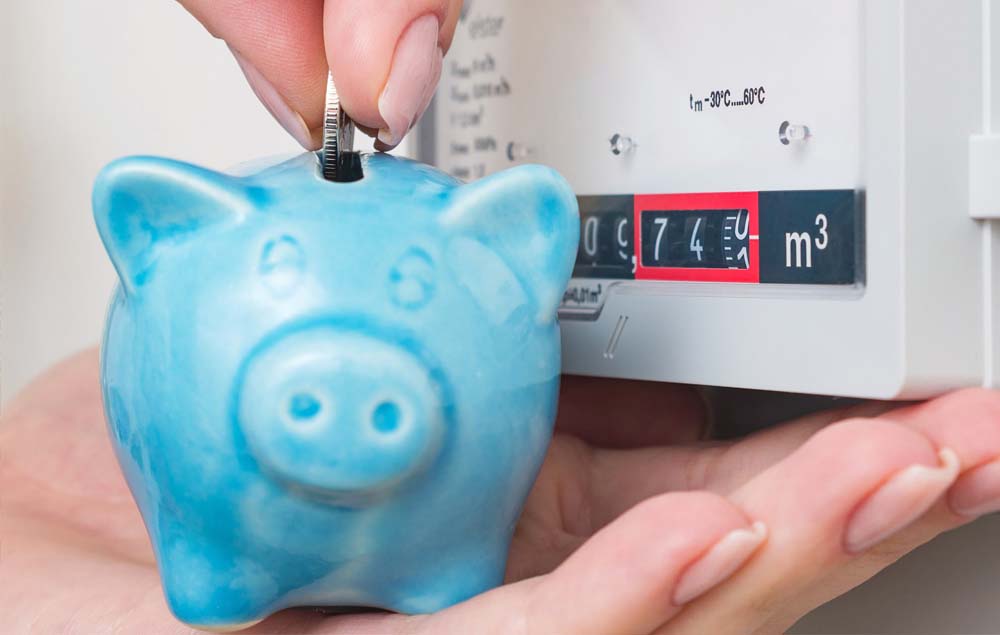 Hand putting money in a piggy bank next to an energy meter